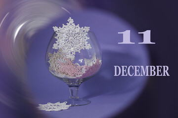 Calendar for December 11: numbers 11, the word December, glass with decorative snowflakes on a...