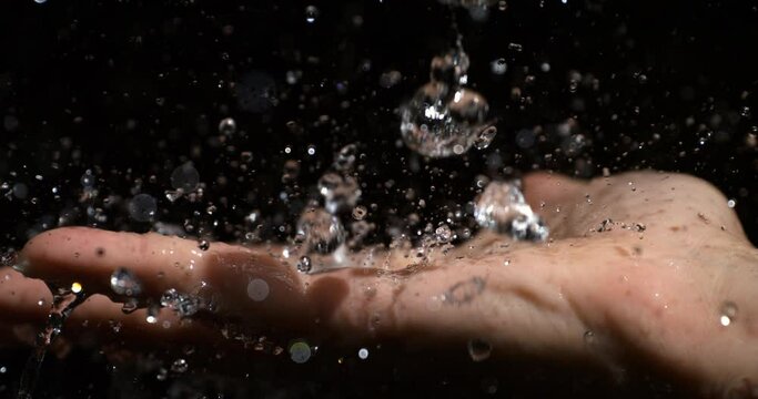 Super slow motion macro of young woman is pouring clean fresh transparent water in her hand while taking hot relaxing outdoor shower in a spa at 1000 fps.