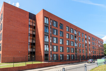 Exterior of a large new apartment building along a street on a sunny day