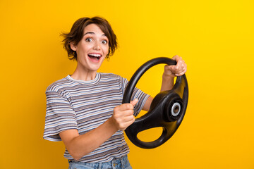 Portrait of impressed ecstatic girl with short hairstyle wear grey t-shirt holding steering wheel...
