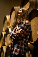 Portrait of a young woman surrounded by wine barrels In her winery