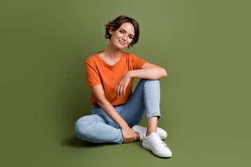 Full size photo of smart good mood woman dressed orange t-shirt jeans in glasses sit on floor...