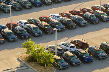Aerial view of dealership parking lot with many brand new cars for sale. Development of american...