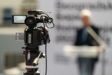 TV camera records a compelling male speaker on stage, delivering impactful insights on fair