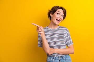 Portrait of impressed girl with short hairdo wear grey t-shirt directing look at discount empty space isolated on yellow color background - obrazy, fototapety, plakaty