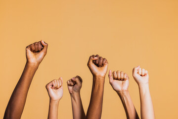 Hands raised with closed fists. Diverse coloured hands raised up with closed fist symbolizing power, determination. - obrazy, fototapety, plakaty
