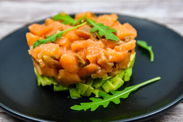 Salmon tartare with arugula on a wooden background