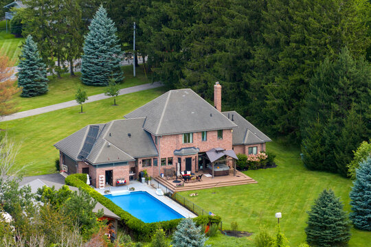 Upscale suburban home with large swimming pool in backyard and green grassy lawn in summer season in upstate New York. Private residential house in rural suburban sprawl area in Rochester, NY
