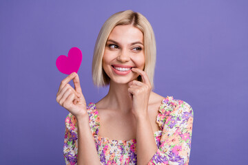 Photo of tricky pretty woman dressed flower print blouse holding pink heart finger lips looking empty space isolated purple color background