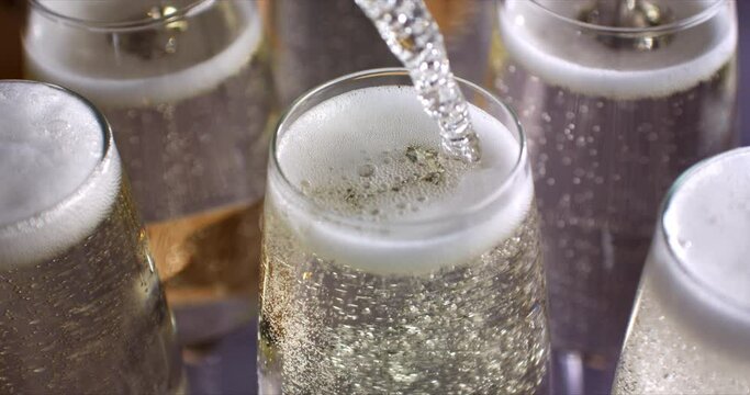 Super slow motion of champagne wine being poured in glasses for toast with wishes of happiness. Christmas celebration or New Year party.