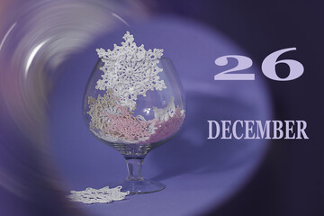 Calendar for December 26: numbers 26, the word December, glass with decorative snowflakes on a...
