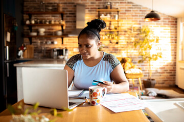 Woman holding credit card with laptop shopping paying bills at home