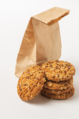 Stack of whole grain cookies with seeds near the craft pack isolated on white background. Organic healthy pastries closeup isolated