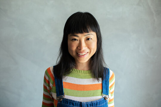 Portrait of a smiling happy Asian woman in casual clothing with grey background