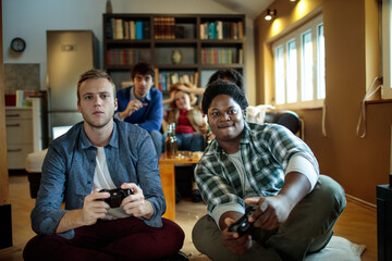 Friends playing video games together, group of young people with game controllers, multiethnic gamers on couch, casual gaming session, fun time at home - obrazy, fototapety, plakaty