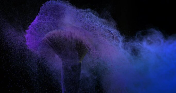 Super slow motion macro of make up brushes with flying colorful cosmetic product powder dust particles splash explosion isolated on dark background.