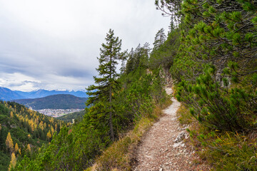 Obraz premium small path on top of a mountain with view towards alpine summits and cloudy sky 