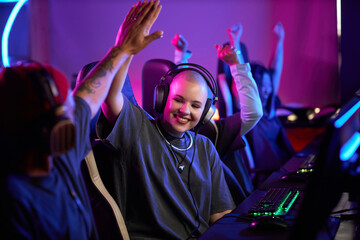 Naklejka premium Portrait of smiling young woman in professional gaming tournament high five teammate and celebrating victory, copy space