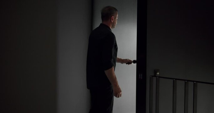 Man in black shirt open room door and go away from home. Male leave apartment. Person enter flat