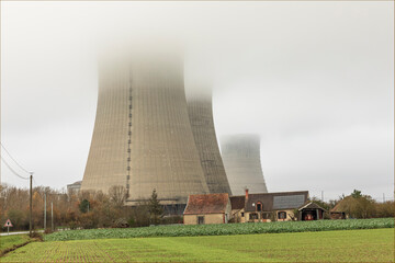 Old french farmhouse under nuclear power station cooling towers