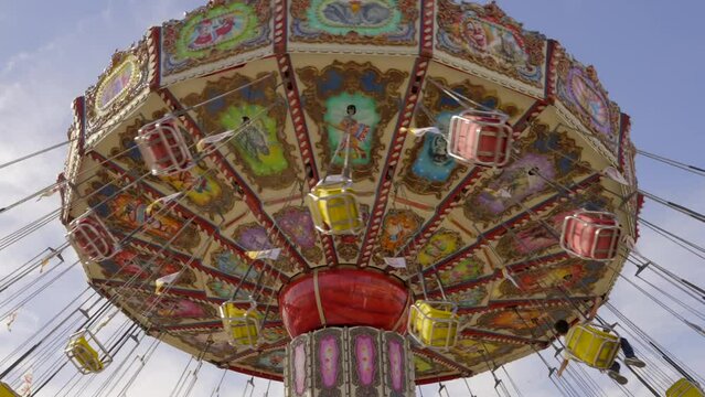 This time lapse shows a swinging and spinning chair ride at a carnival with a blue sky in the background.