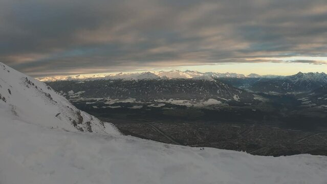 SLOW MOTION SHOT - View from the Hafelekarspitze mountain over the city of Innsbruck, Austria, the Inn Valley, and the landscapes beyond.