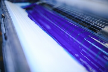 blue ink on rollers of industrial offset printer during work in typography workshop
