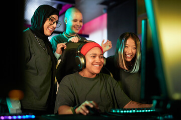 Diverse group of young women playing videogames and cheering for teammate in eSports competition © Seventyfour