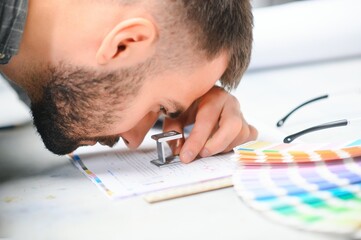 Graphic engineer or worker checking imprint quality in modern print shop