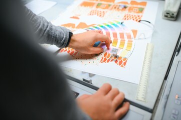 Printing house interior with modern offset print machine and operator in working uniform checking...