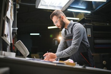 Graphic engineer or worker checking imprint quality in modern print shop