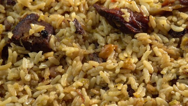 Pilaf macro rotates on a plate. Traditional East Asian dish with chickpeas, barberries, cumin, long grain rice and lamb