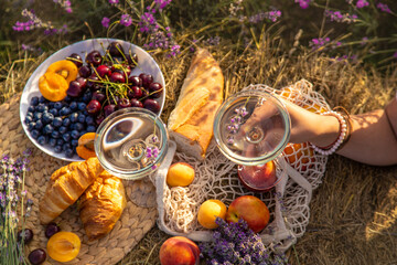 A woman drinks wine in a lavender field. Selective focus.