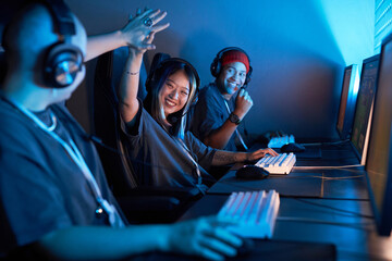 Portrait of Asian young woman playing video games and celebrating victory in blue light - obrazy, fototapety, plakaty
