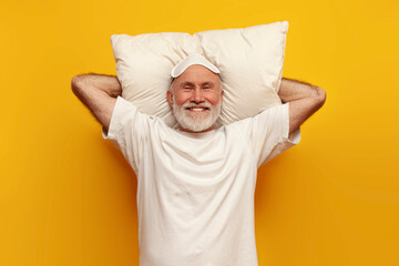 old bald grandfather in white sleep mask lies on soft comfortable pillow and rests on yellow...