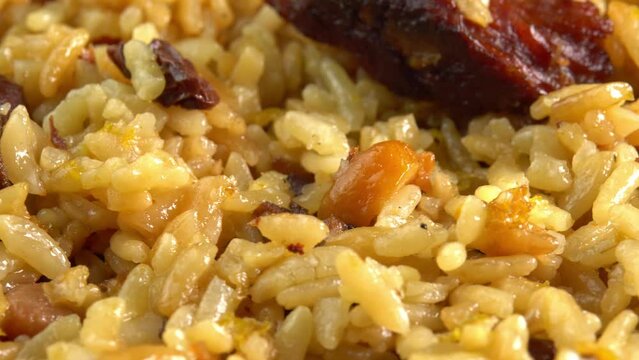 Uzbek pilaf macro rotates side view. Traditional East Asian dish with chickpeas, barberries, cumin, long grain rice and lamb