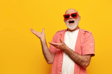 cheerful crazy old bald grandfather in summer shirt and sunglasses shouts and points with his hands...