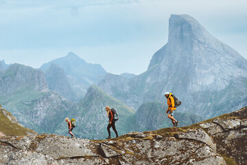 Family hiking together in Norway mountains, active vacations outdoor. Parents and child traveling healthy lifestyle adventure trip with mother, father and kid climbing in Lofoten islands - obrazy, fototapety, plakaty