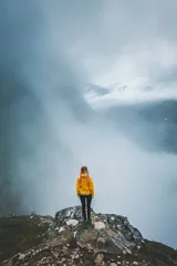 Zelfklevend Fotobehang Woman tourist hiking alone in foggy mountains Norway, girl enjoying misty view adventure vacations healthy outdoor lifestyle, moody landscape © EVERST