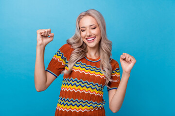 Photo of lucky shiny girl dressed print shirt shouting yes rising fists closed eyes isolated blue color background - obrazy, fototapety, plakaty