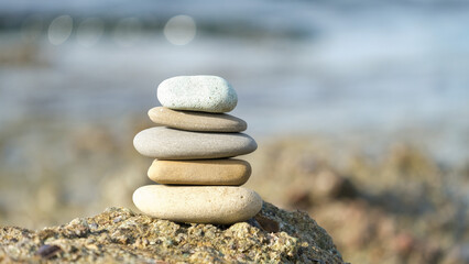 Fototapeta na wymiar Stone cairn pyramid at seaside. Stack of balanced stones on the beach. 