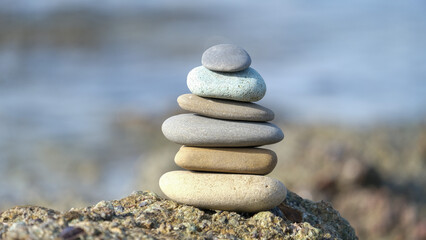 Fototapeta na wymiar Stone cairn pyramid at seaside. Stack of balanced stones on the beach. 
