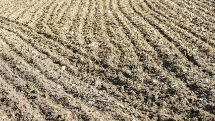 Close up ploughed land soil with tractor wheel trail.