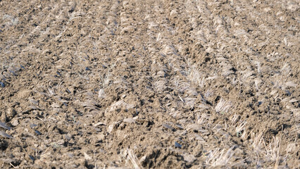 Close up ploughed land soil with tractor wheel trail.