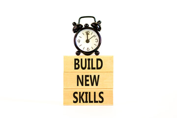 Naklejka premium Build new skills symbol. Concept word Build new skills on beautiful wooden block. Black alarm clock. Beautiful white table white background. Business, education build new skills concept. Copy space.