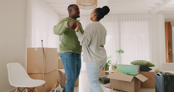 Dancing, happy couple and celebrate moving house with boxes in a room. New home, fun energy and love of excited black man and woman at property with commitment, care or support for homeowner mortgage