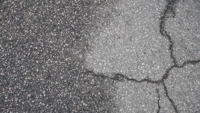 Top down view of crack on asphault street half covered in water