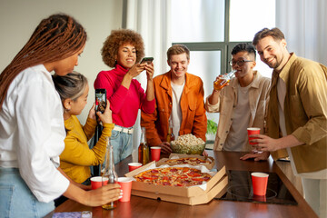 multiracial group of young people at house party ordered pizza and beer and photographed the food...