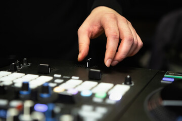 Naklejka premium DJ using cross fader on a sound mixer to scratch vinyl records on a hip hop party