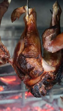 hanging roast suckling pig leg cooked on a restaurant grill.